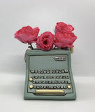 Allen Designs Baby Blue Typewriter Planter. Pictured with pink roses