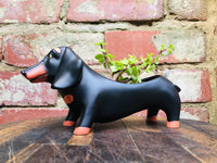 Baby Dachshund Planter by Allen Designs. Pictured against a rustic brick wall, planted with succulents
