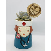 Baby Healthcare Hero Planter with Red Hair by Allen Designs. Pictured planted with a succulent and displayed with a healthcare hero timber plant tag