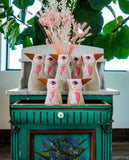 A group of white bird vases or watering cans by Allen Designs. Pictured on vintage furniture with dried flowers